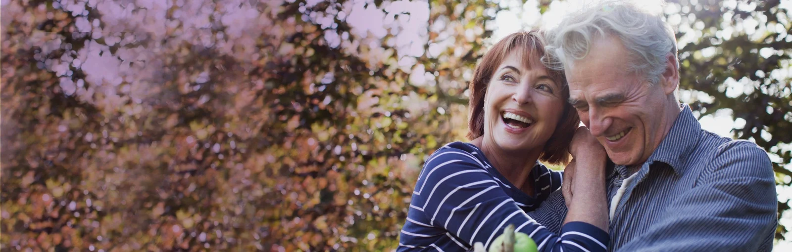 elderly couple walking through forest and smiling