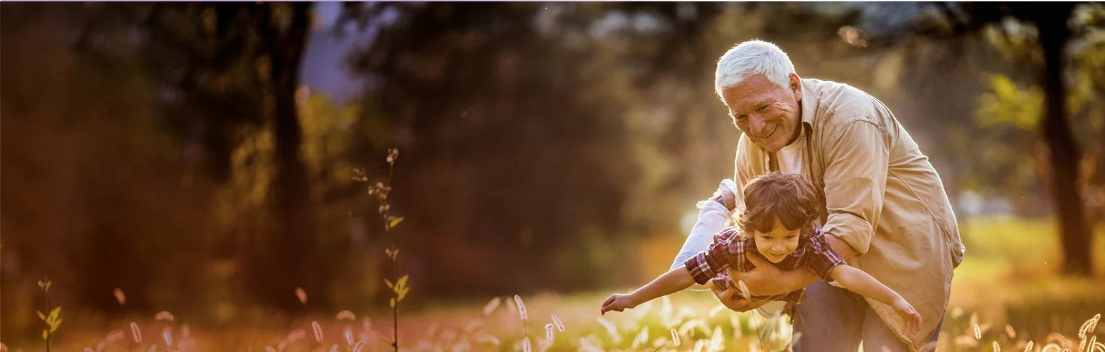 elderly man plays with grandson in field