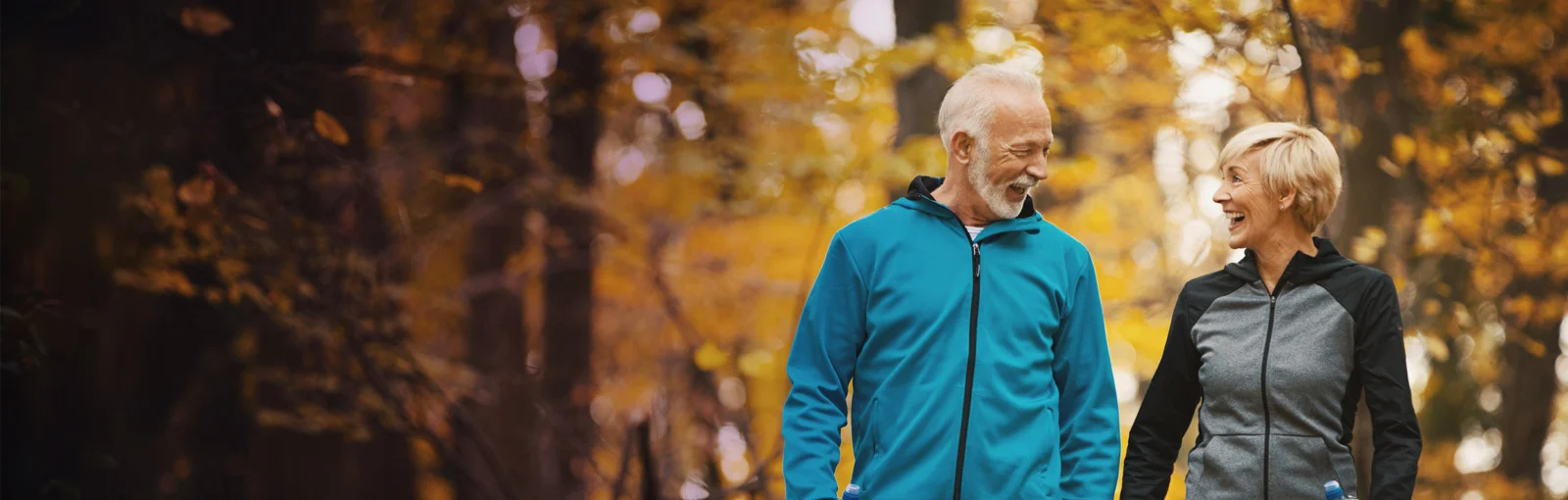 elderly couple walking on a park trail
